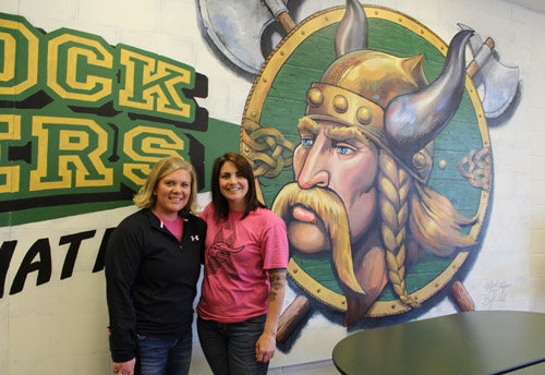 Two teachers in front of mascot
