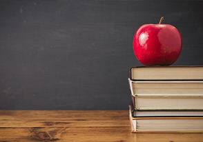 Apple with books by chalkboard